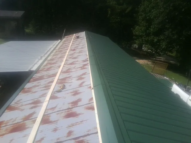 Old rusted panels beside newly installed green metal roofing — Wind Damage Roof Repair by Roofing Brothers in Sutton