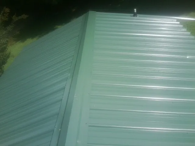 New green metal panels meeting at the ridge of a roof — Flat Roof Repair work by our crew in Sutton