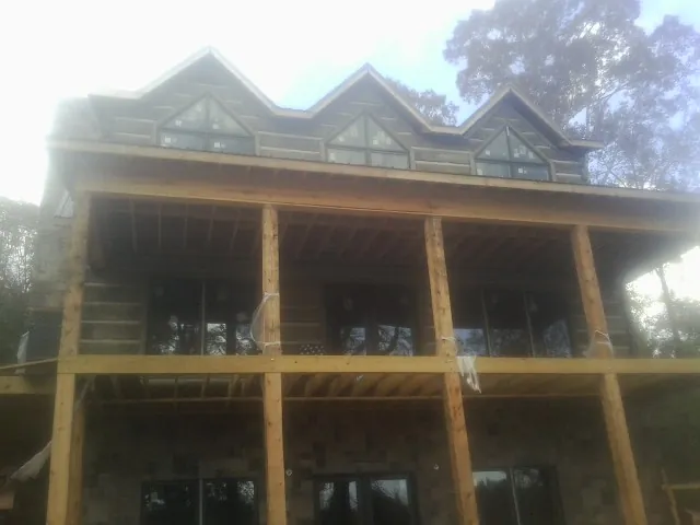 Dormers and porch framing on a large log home under construction — Roof Coating work by our crew in Sutton